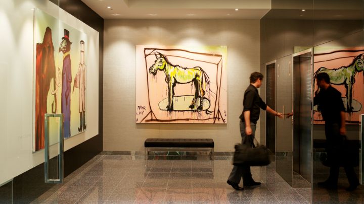 A man pressing an elevator button in a hotel lobby with paintings on the walls