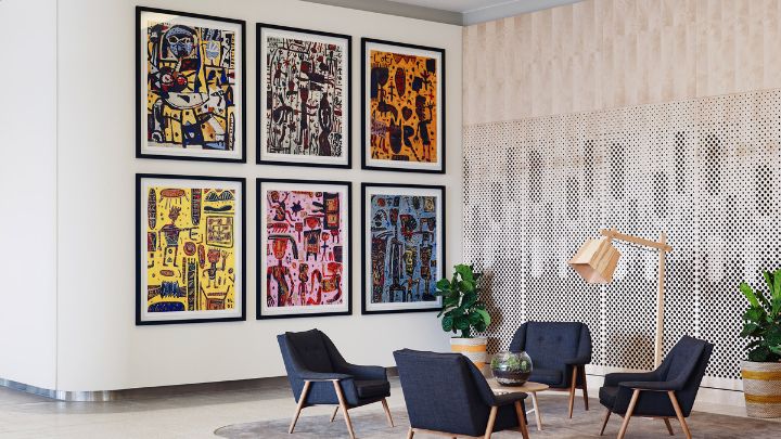Four dark blue chairs inside a hotel with colourful paintings on the wall